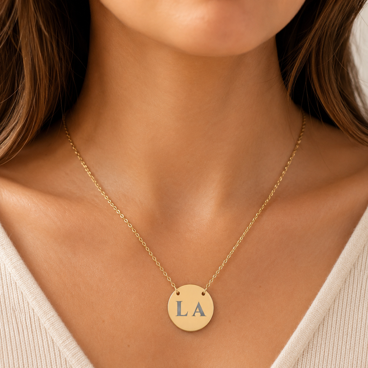 Close-up of laser-engraved custom letters on the polished circular gold disc pendant