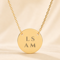 Personalized name necklace with custom engraved text 'LS AM' on gold circle pendant with spacing